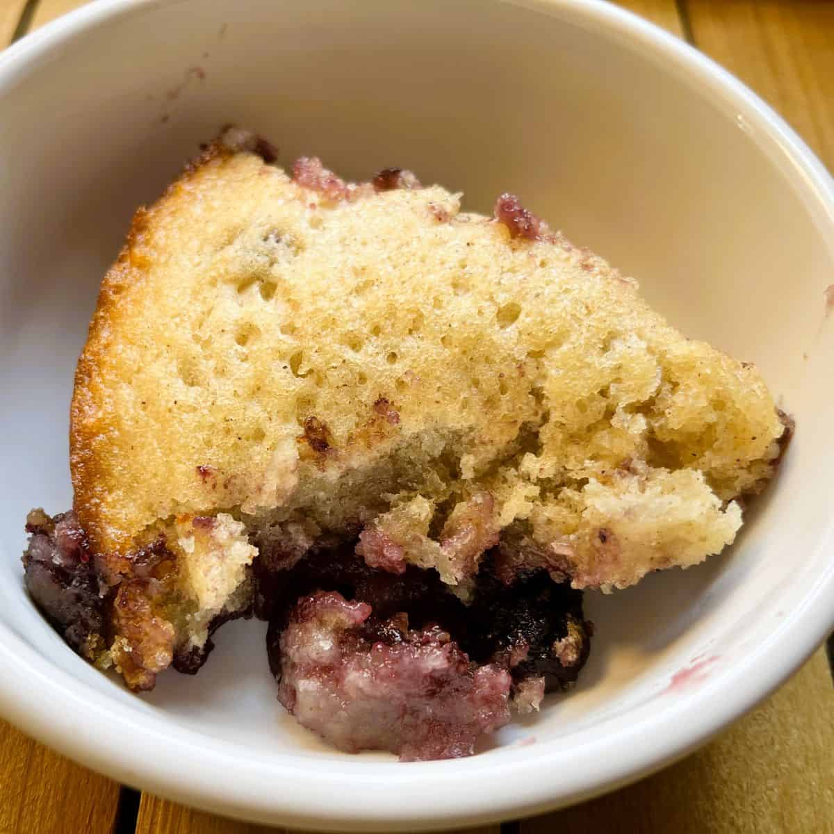 closeup of fruit cobbler in a white bowl on a wooden tray