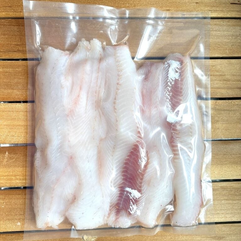 fresh fish fillets in a vacuum sealed plastic bag sitting on a wooden tray